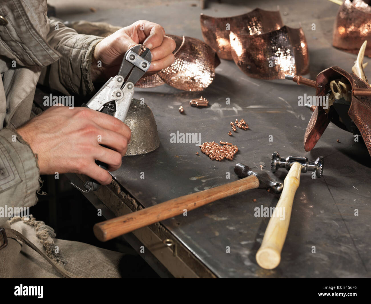 Immagine ritagliata di fabbri mani lavorando con rivetti in rame Foto Stock