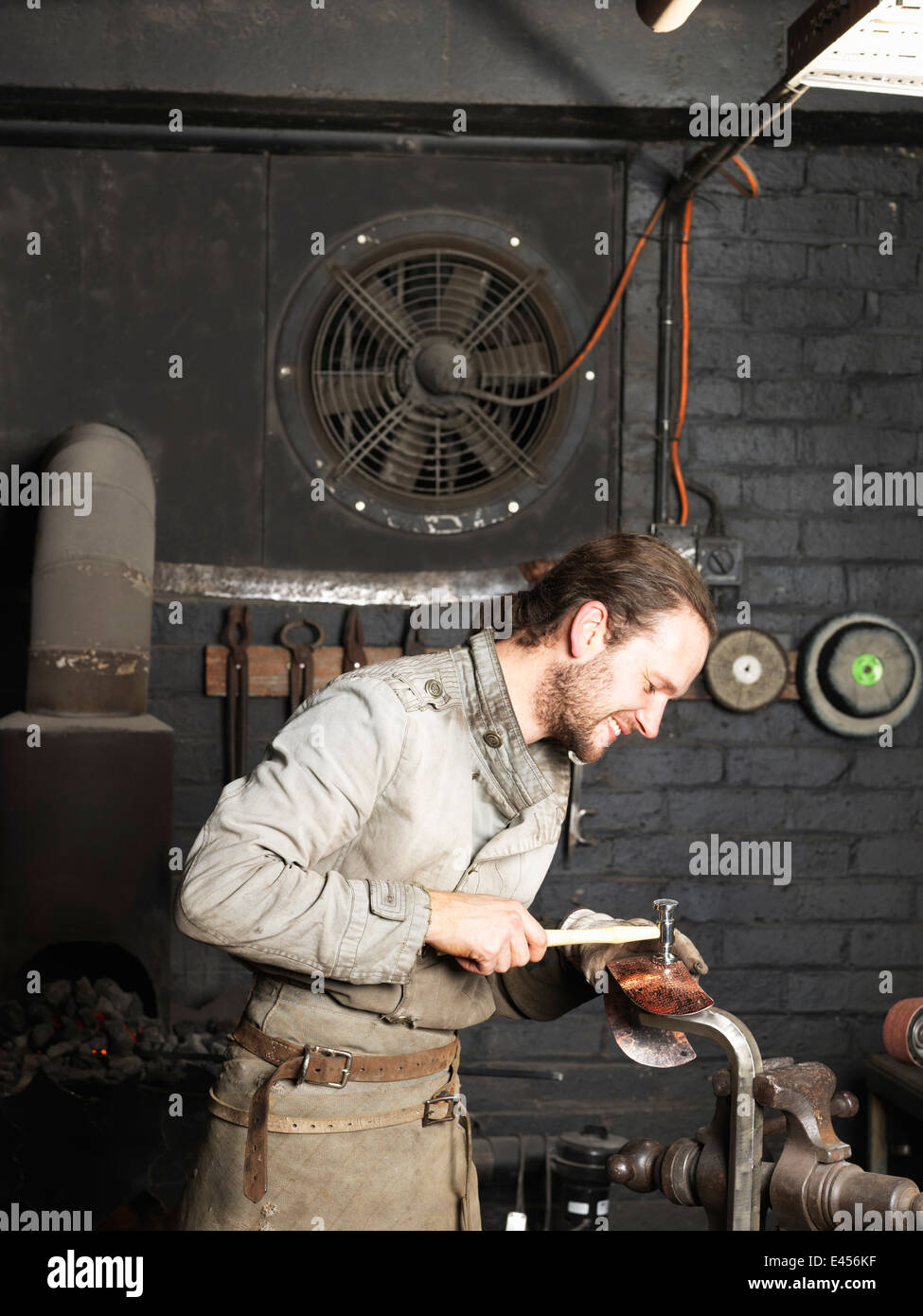 Fabbro martellare il rame in officina Foto Stock