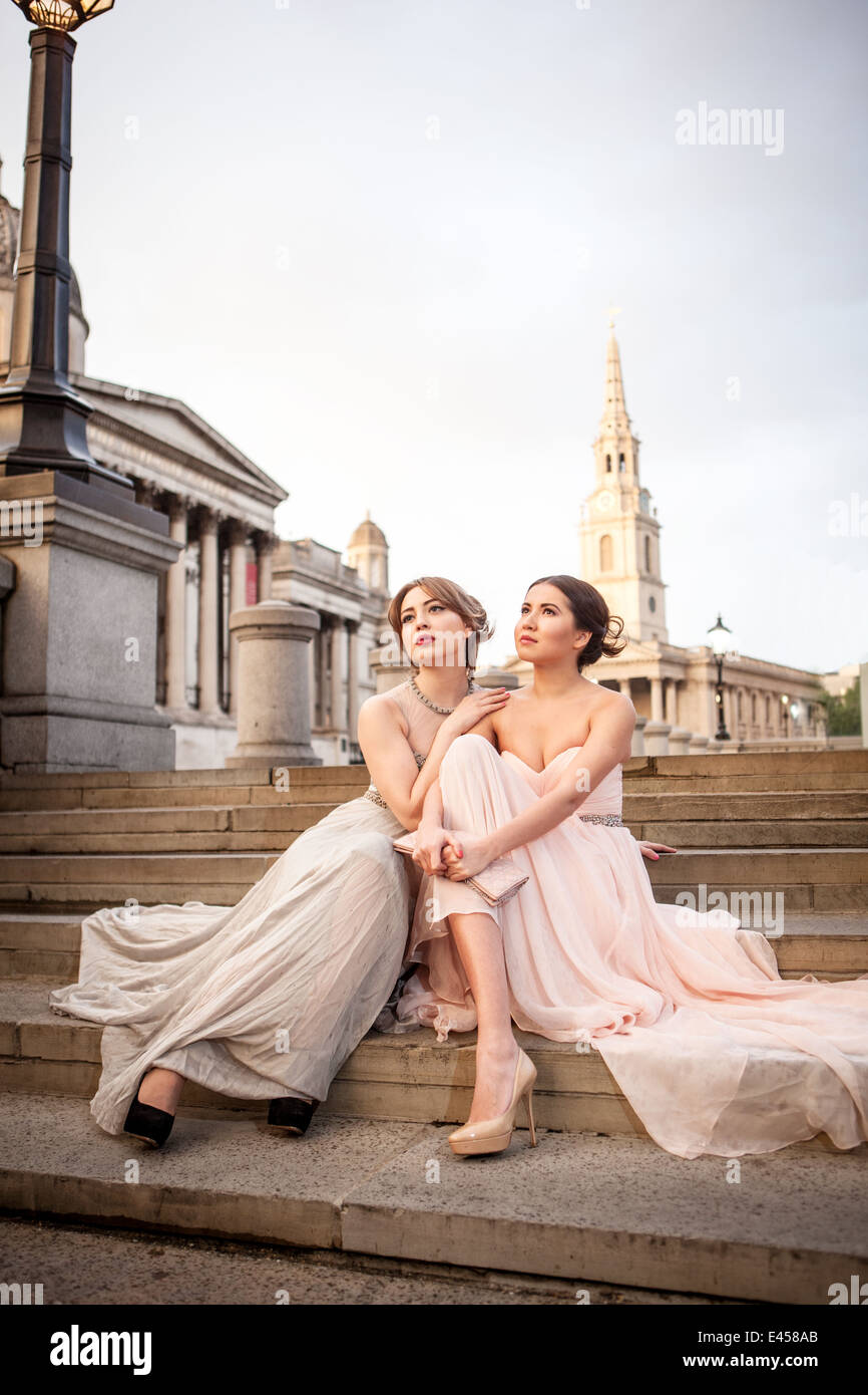 Ritratto di due modelli femminili in posa sui gradini, Trafalgar Square, London, Regno Unito Foto Stock