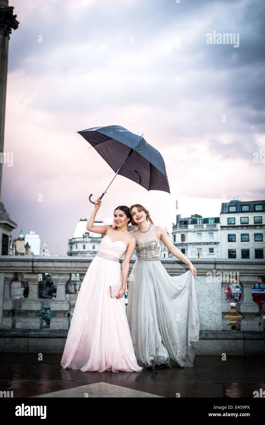 Ritratto di due modelli femmina tenendo premuto fino ombrello, Trafalgar Square, London, Regno Unito Foto Stock