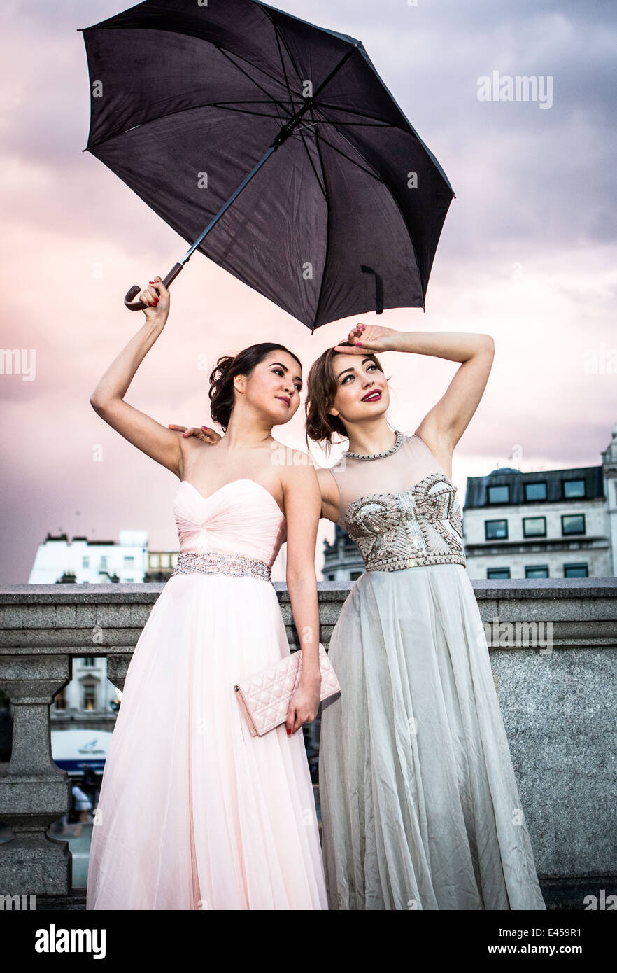 Ritratto di due modelli femminili in posa con ombrellone, Trafalgar Square, London, Regno Unito Foto Stock