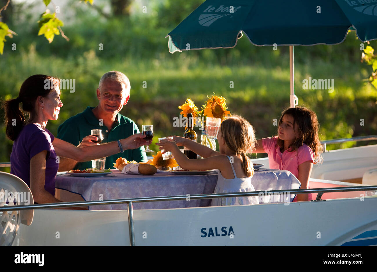 Famiglia avente la cena sul Canal Du Midi vicino a Port de Bram, Francia meridionale. Luglio 2009. Modello di proprietà e rilasciato. Foto Stock