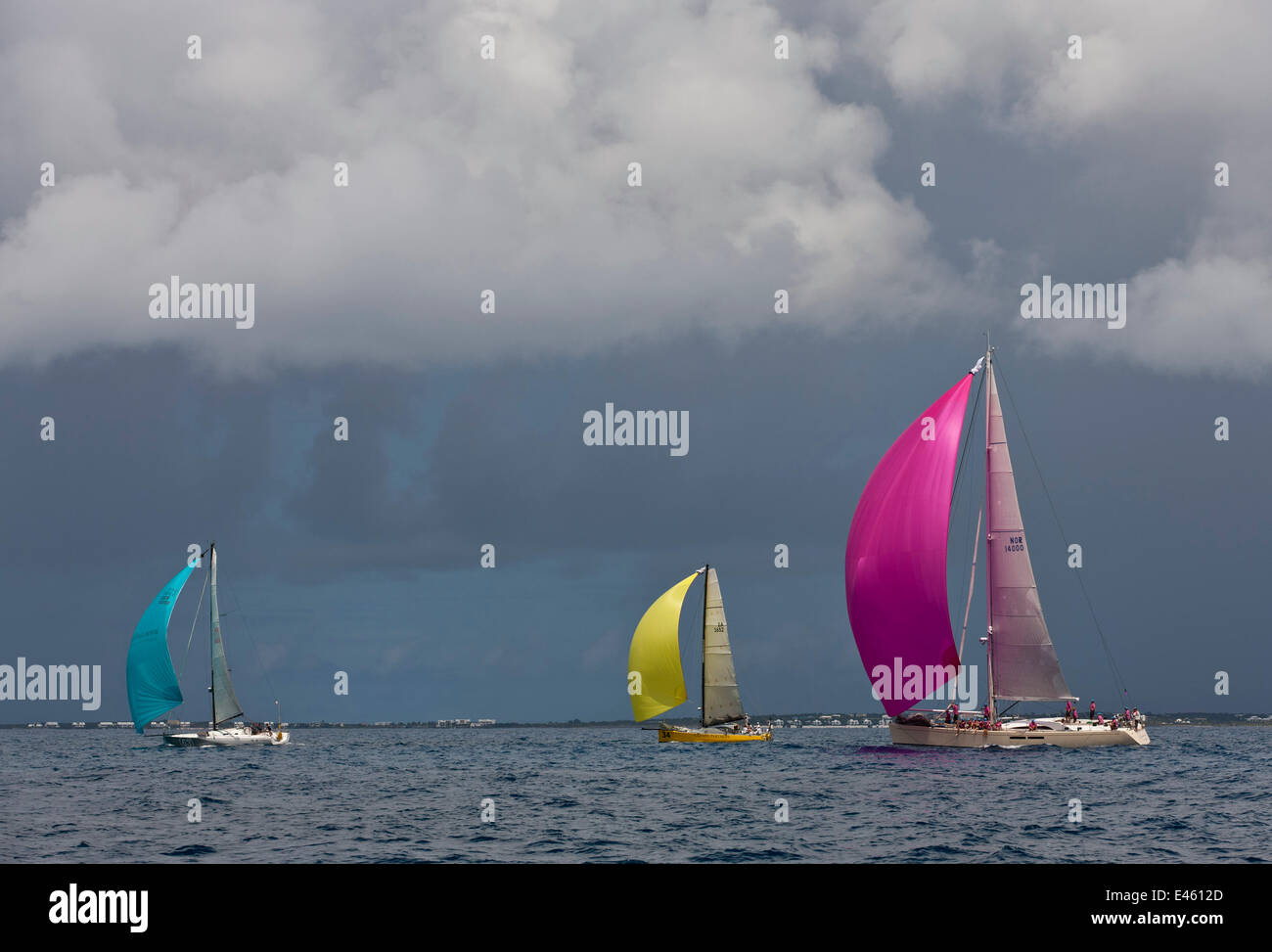 Yachts racing sotto spinnaker colorati e cieli bui durante la regata Heineken, St Martin, Caraibi, marzo 2011. Foto Stock