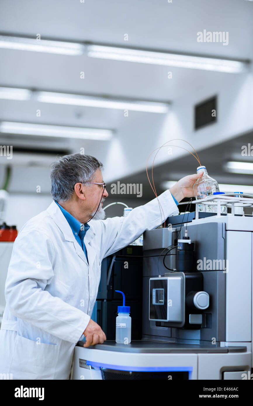 Maschio senior researcher di effettuare attività di ricerca scientifica in un laboratorio (SHALLOW DOF; dai toni di colore immagine) Foto Stock