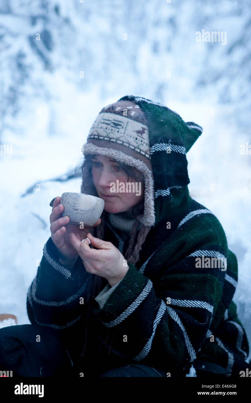 Donna seduta e bere al di fuori, Riisitunturi National Park, Lapponia, Finlandia, Febbraio Foto Stock