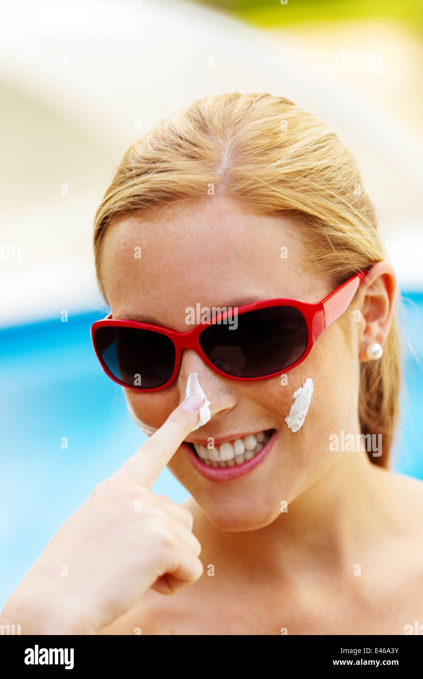 Giovane donna con occhiali da sole in estate e crema solare Foto Stock