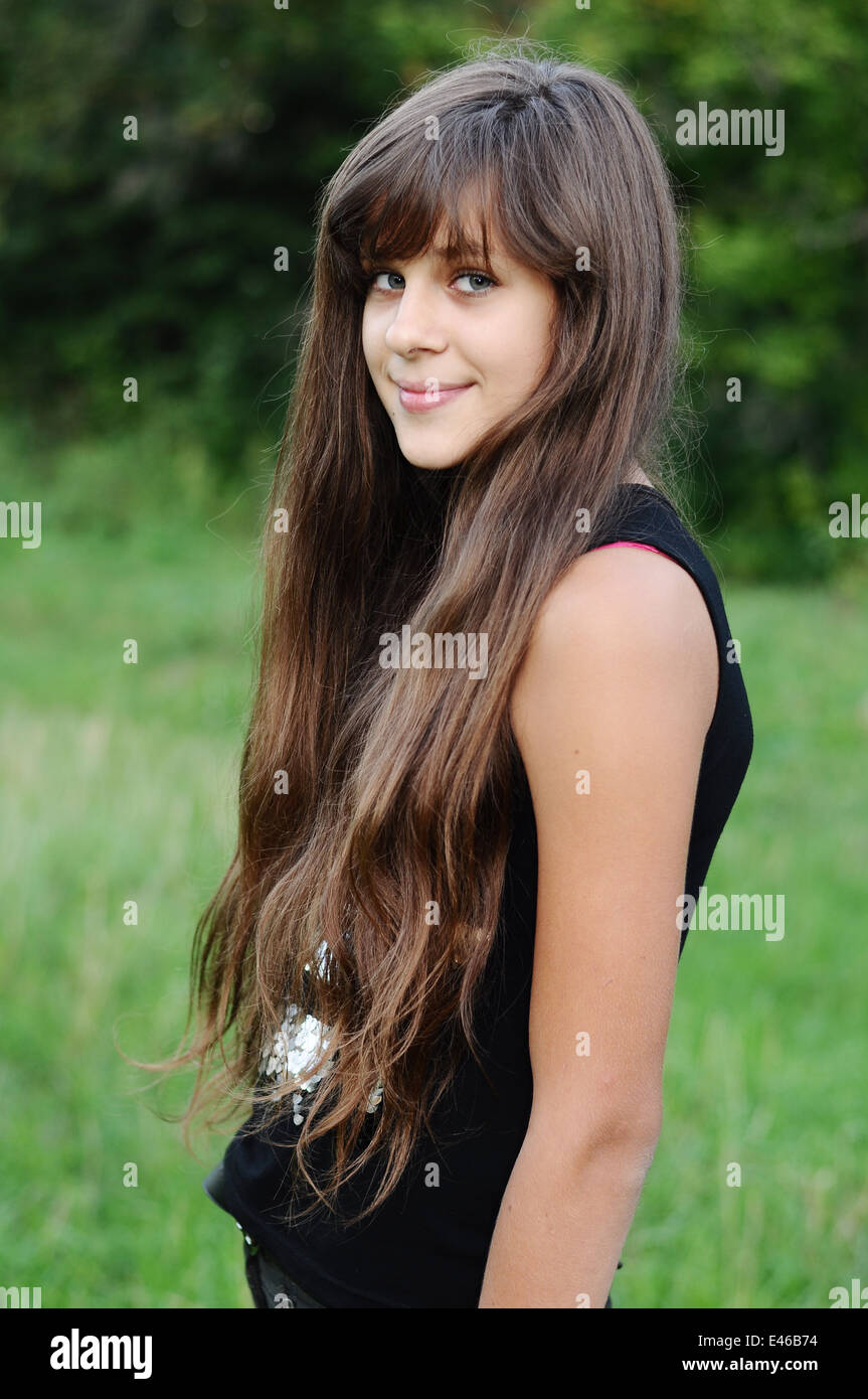 Girl Teen adolescente di età di transizione 13 14 15 anni brunette capelli scuri lungo il parco di natura aria aperta bel ritratto maglietta permanente Foto Stock