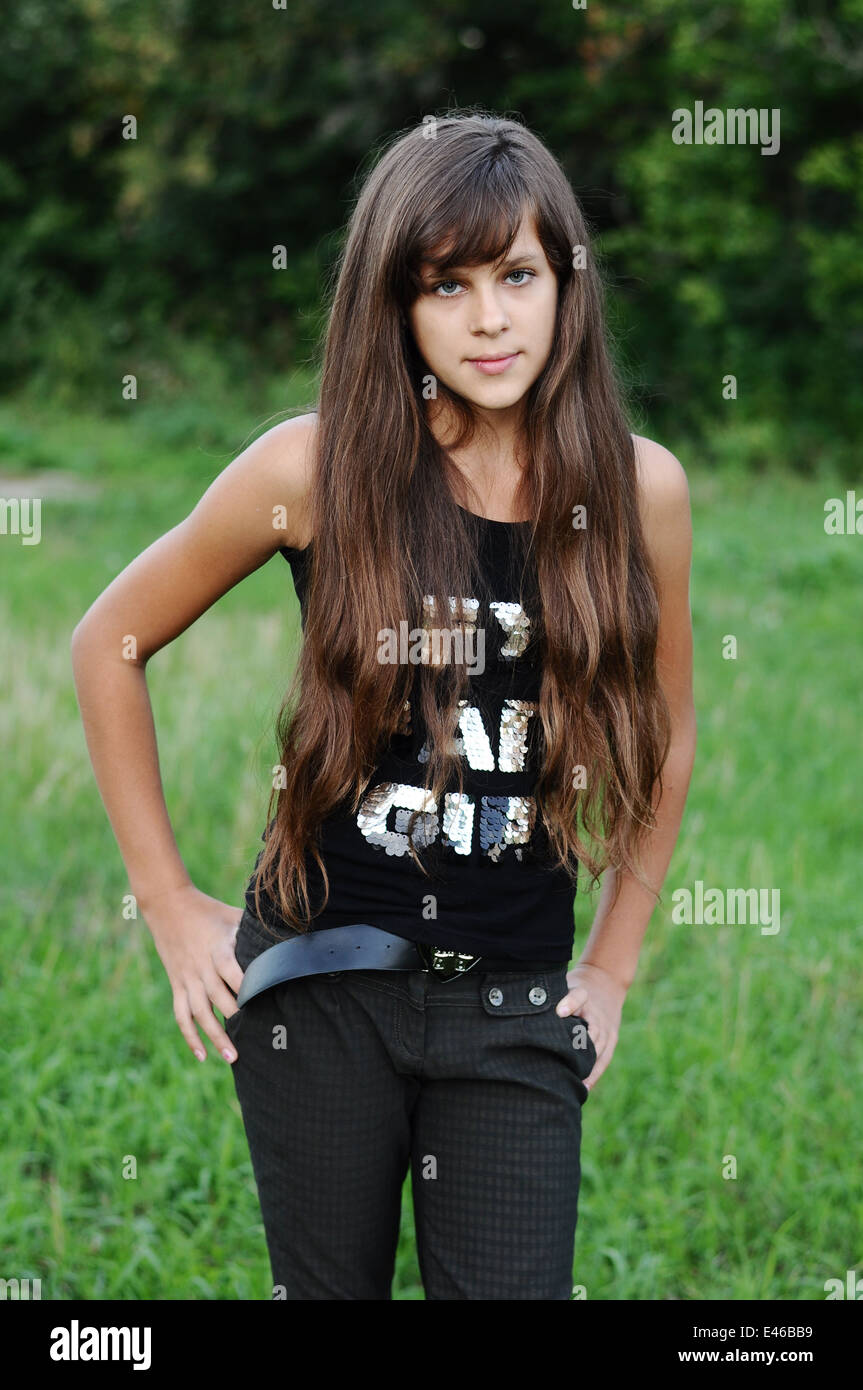 Girl Teen adolescente di età di transizione 13 14 15 anni brunette capelli scuri lungo il parco di natura aria aperta bel ritratto maglietta permanente Foto Stock