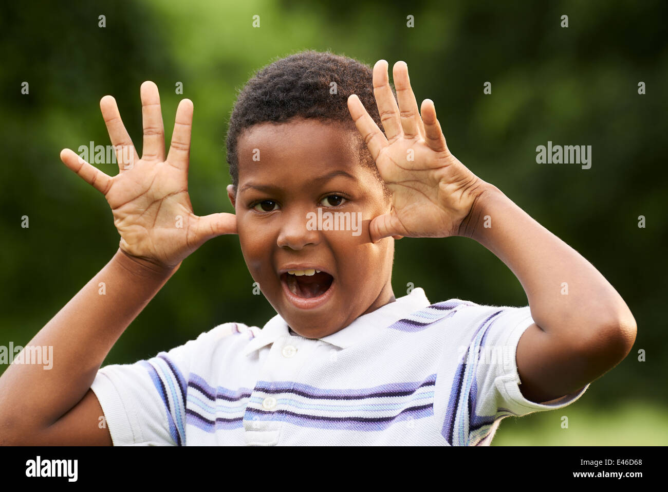 Ritratto di felice bambino nero facendo una faccia e smorfie a videocamera all'esterno in posizione di parcheggio Foto Stock