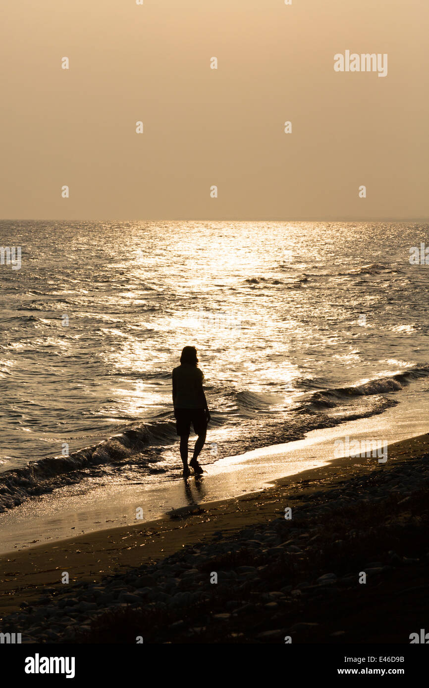 Silhouette di donna che cammina sulla spiaggia al tramonto, Pervolia, Cipro  Foto stock - Alamy
