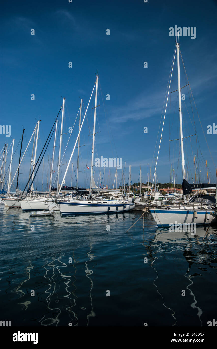 Yacht di lusso in blu e bianco ormeggiato a Saint Tropez su una bella giornata di sole e sotto un cielo blu con wispy blue clouds. Foto Stock