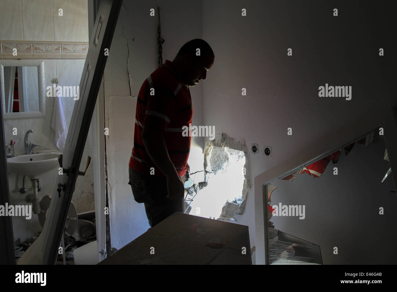 Sderot, Israele. 3 Luglio, 2014. Un uomo israeliano ispeziona i danni di una casa in seguito a un attacco di proiettile da militanti di Gaza Sderot, Israele, il 3 luglio 2014. In precedenza il giovedì, tre proiettili ha colpito edifici residenziali nella città israeliana di Sderot, tra i quali era un appartamento che serve come un asilo nido privato scuola. Razzi lanciati durante la notte ha messo k.o. elettricità in alcune parti della città. La maggior parte degli altri proiettili sparati giovedì ha colpito aree aperte, che non provoca lesioni. Credito: Xinhua/Alamy Live News Foto Stock