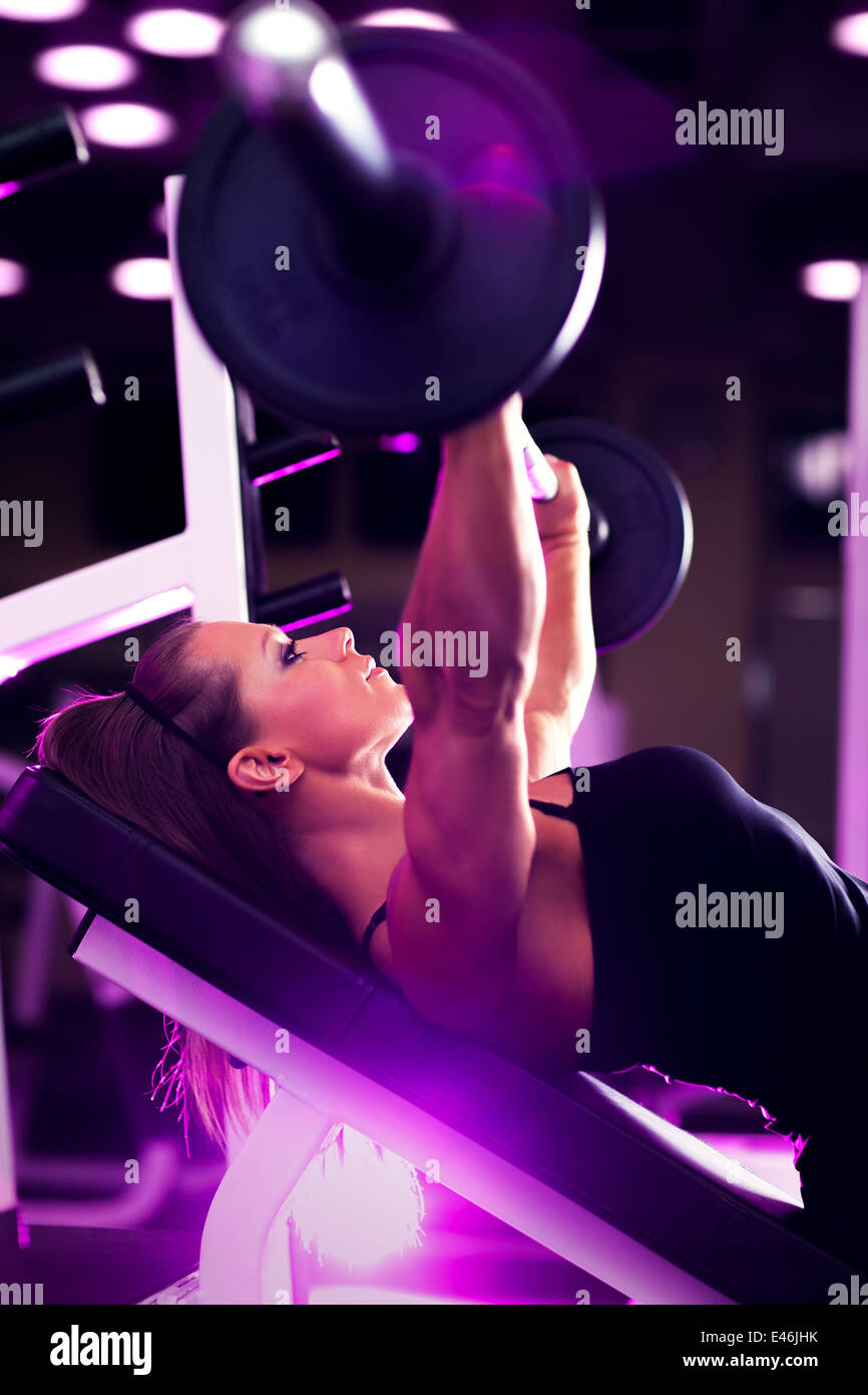 Giovane donna culturista con barbell. Tinta di rosa. Foto Stock