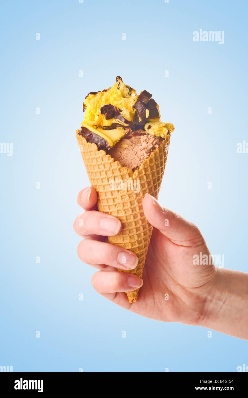 Donna mano che tiene il gelato al cioccolato in un cono. Foto Stock