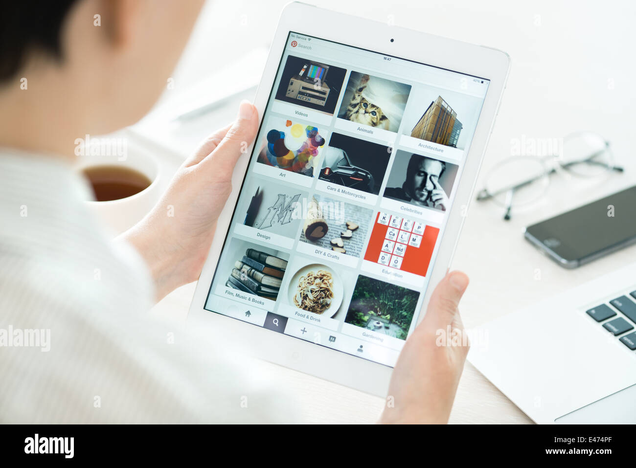 Donna che guarda su Pinterest le schede di applicazione sul moderno bianco Apple iPad aria, il quale è stato progettato e sviluppato da Apple Inc. Foto Stock