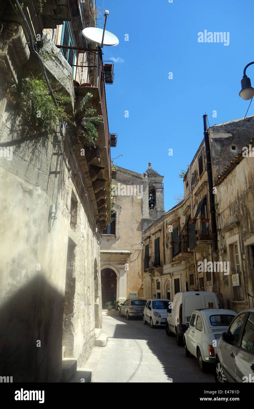 Ragusa, Sicilly- affascinanti e pittoreschi tetti di terracotta, le campane della chiesa, un medley di ristoranti strade strette causano il parcheggio auto Foto Stock
