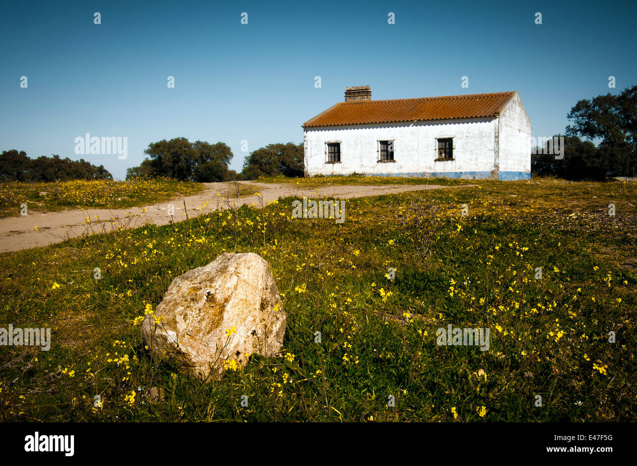 Poco bianco casa rurale abbandonata in campagna con una roccia in primo piano Foto Stock
