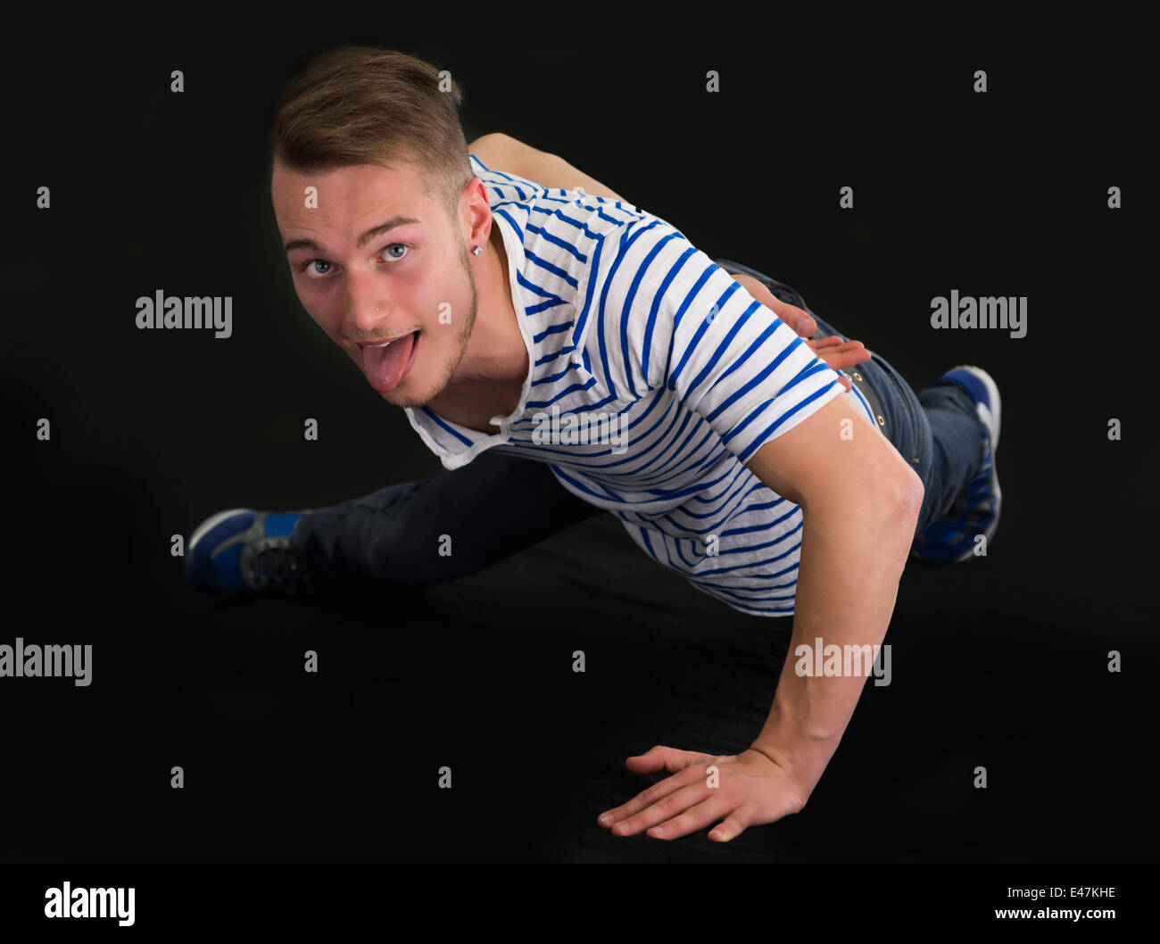 Bel giovane facendo mano singola push-up, isolato su sfondo nero Foto Stock