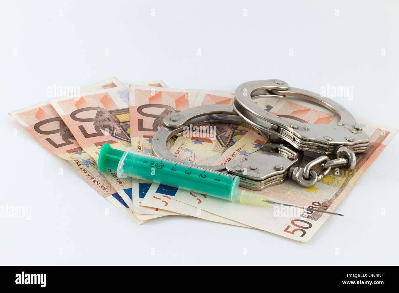 Le manette e la siringa sul denaro bollette Foto Stock