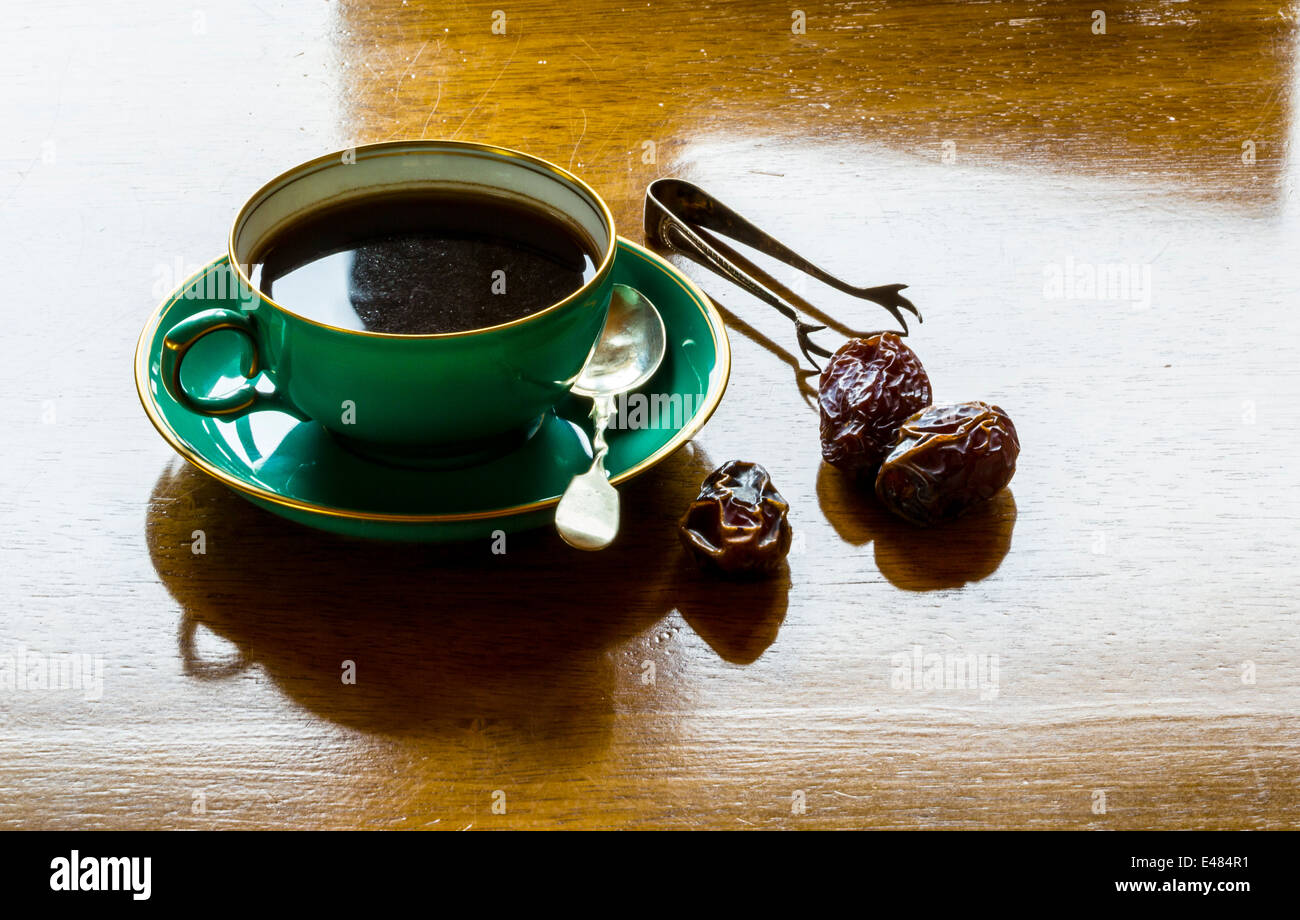 Una tazza di forte caffè nero con date e pinze Foto Stock