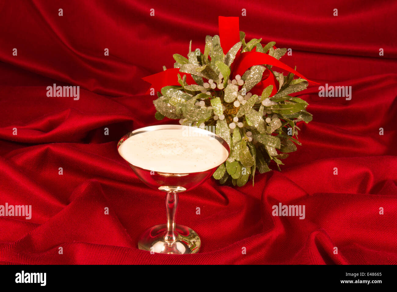 Argento tazze riempite con zabaione su sfondo rosso con vischio Foto Stock