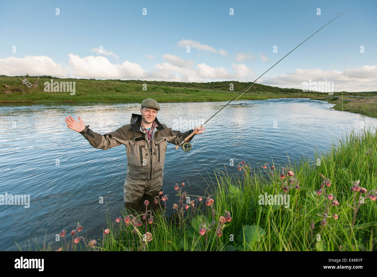 Flyfisherman che mostra la dimensione di un pesce che appena ha preso il via Foto Stock