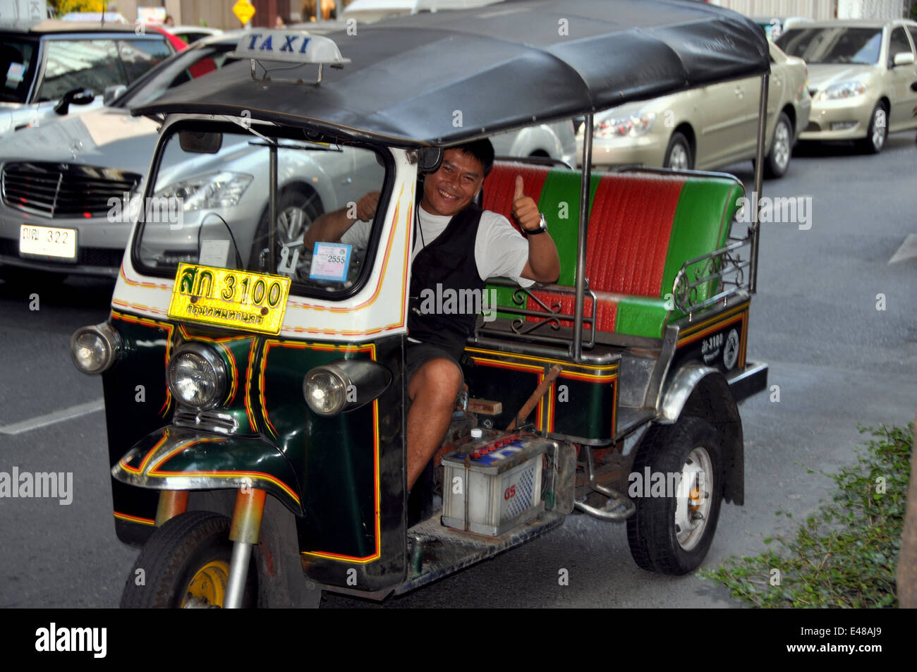 BANGKOK, Thailandia: un sorridente tuk-tuk taxi driver in seduta del traffico sulle Thanon Rama I nel centro di Bangkok Foto Stock