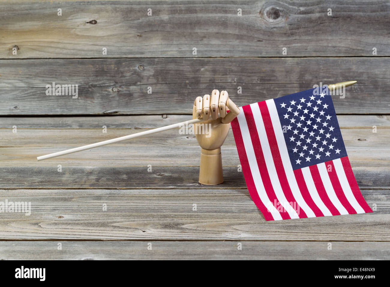 A mano in legno azienda bandiera americana con rustiche tavole in legno in background Foto Stock