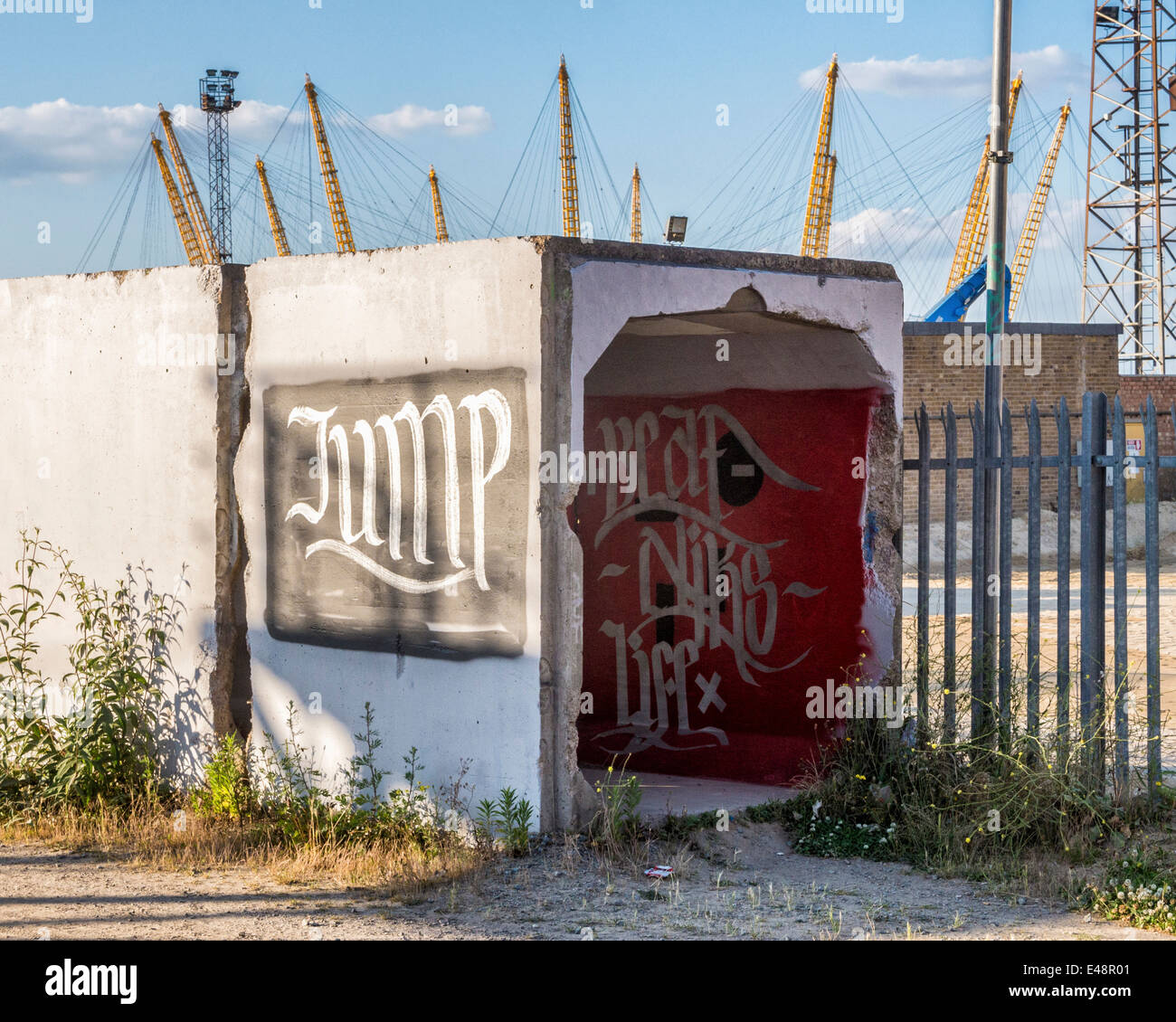 Urban Wasteland - Vecchio coperto di graffiti di blocchi di cemento vicino al sito di costruzione lungo il Tamigi percorso, penisola di Greenwich, London, Regno Unito Foto Stock