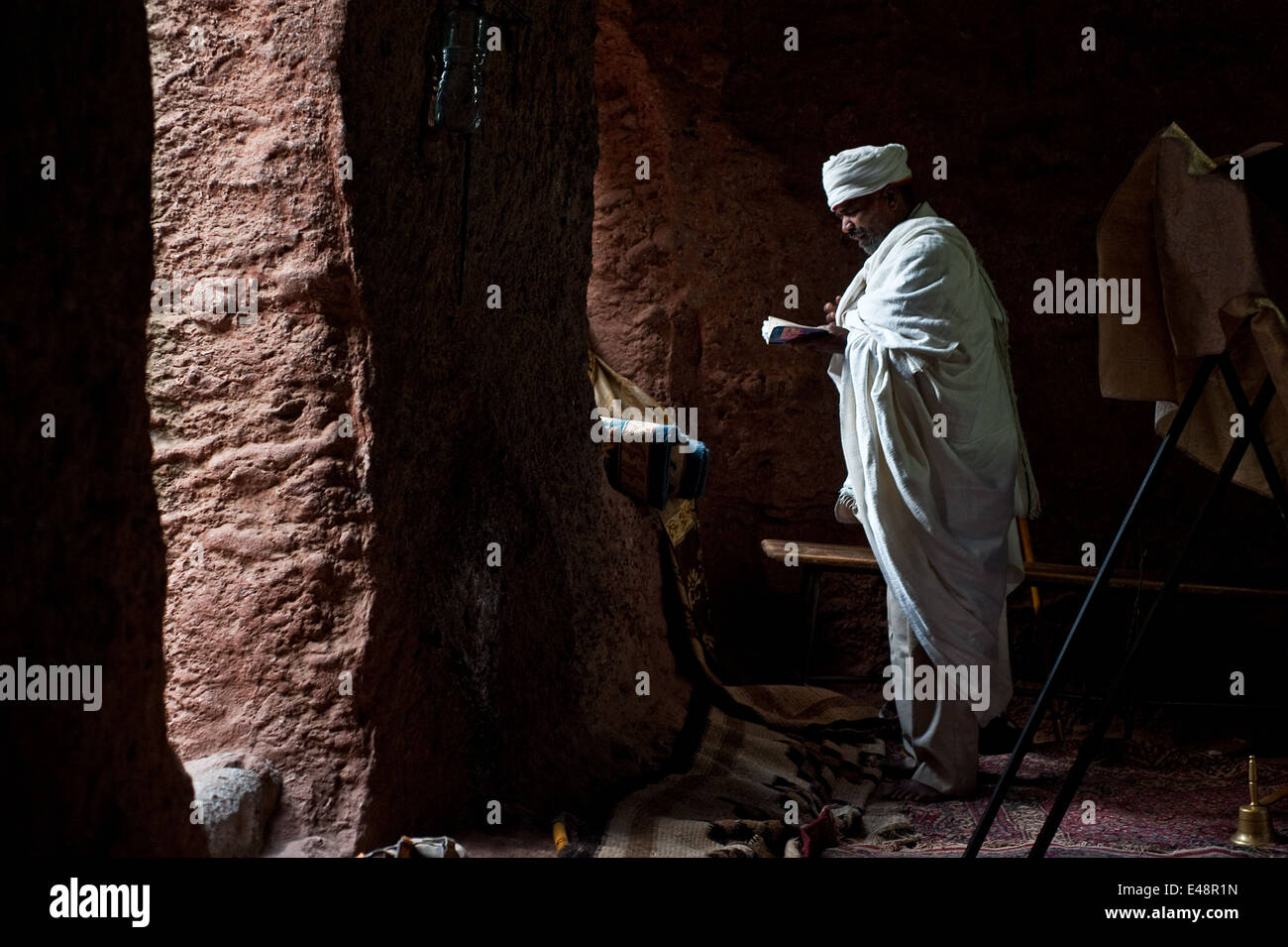 Sacerdote ortodosso dicendo la massa in una roccia scavate chiesa ( Etiopia) Foto Stock