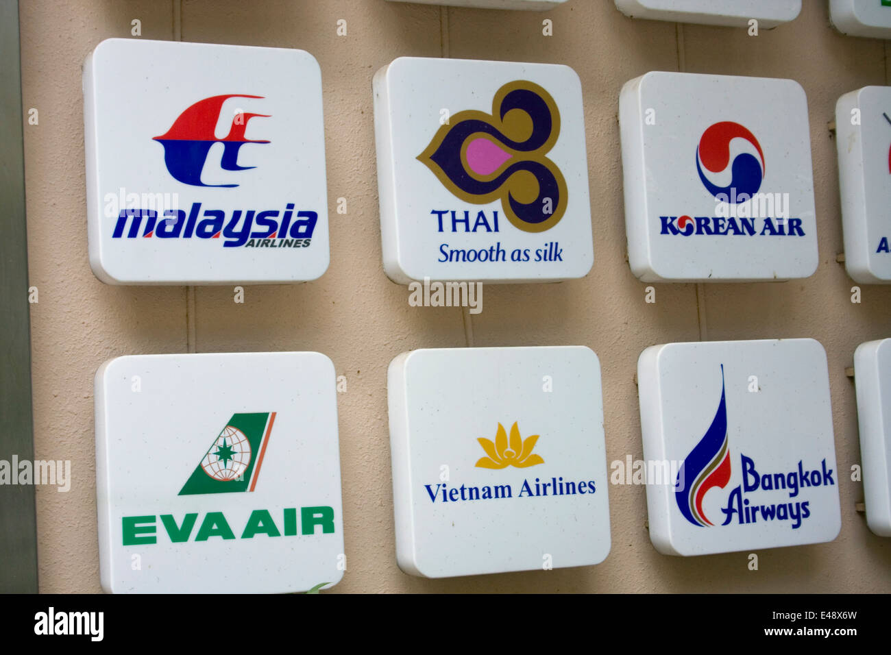 Firma con la compagnia aerea asiatica loghi sono fissati ad una parete in corrispondenza di una agenzia di viaggio in Phnom Penh Cambogia. Foto Stock