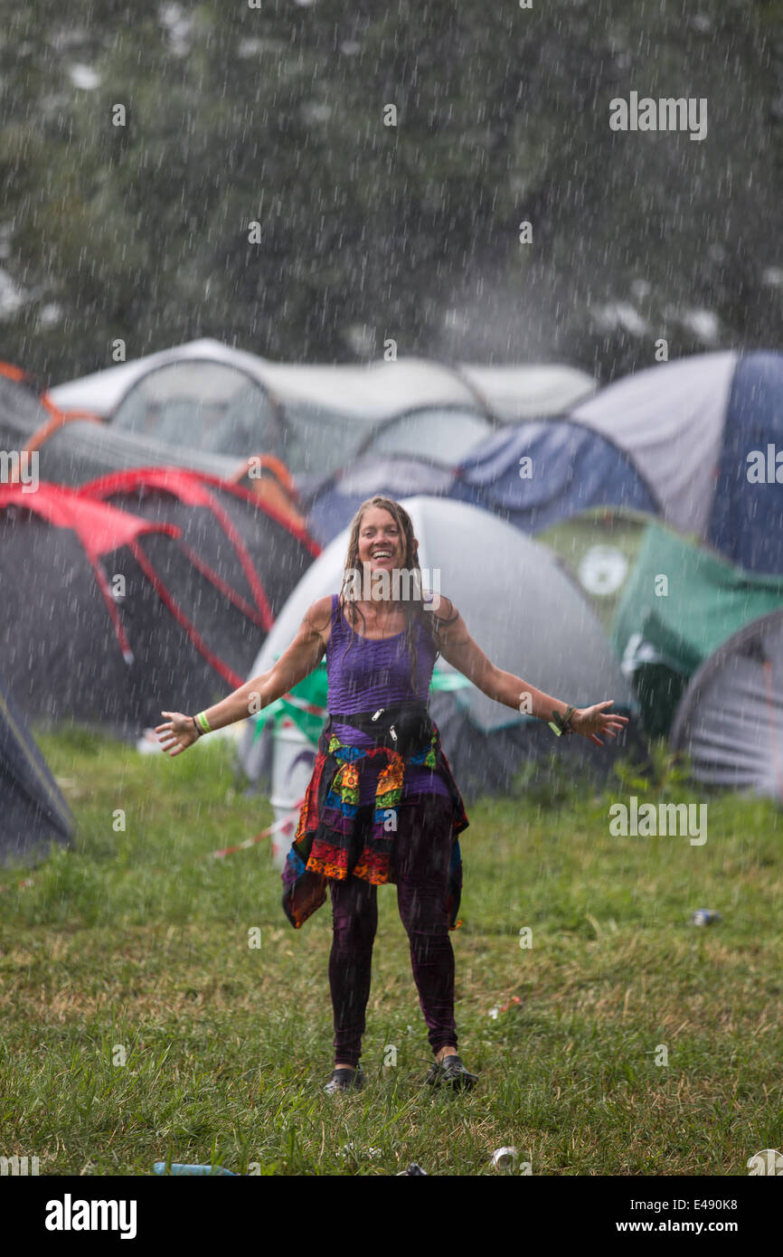 Donna felice Dancing in the Rain vicino a John Peel stage, durante la tempesta elettrica a Glastonbury Festival 2014 Foto Stock