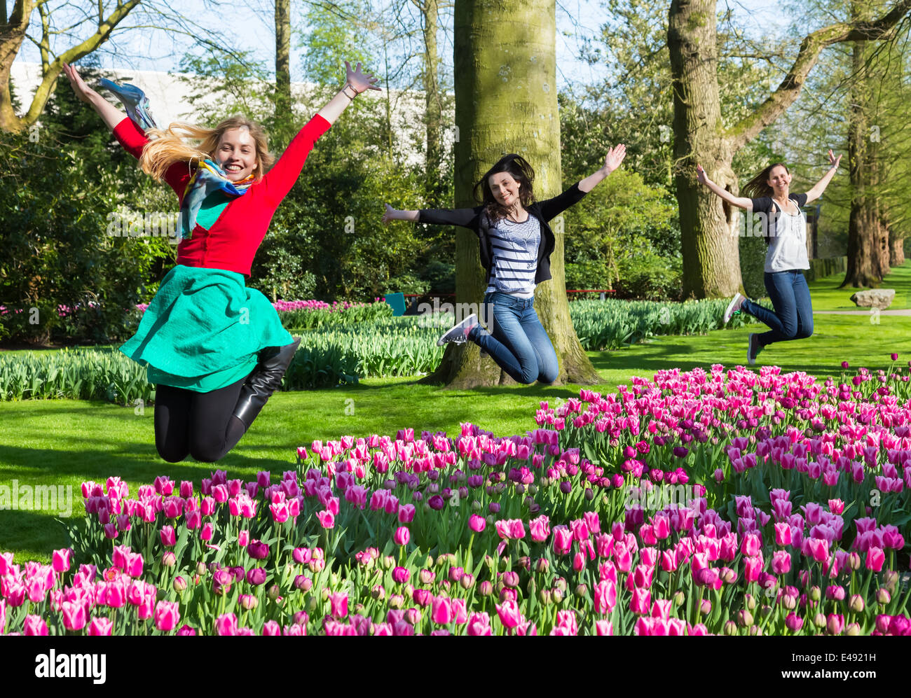 Le tre ragazze saltando sopra il campo dei fiori Foto Stock