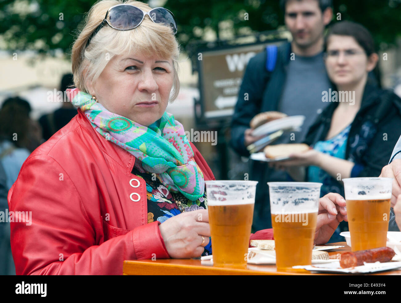 Turisti di Praga nella Piazza della Città Vecchia, una donna che mangia in strada fast food, birra salsiccia Praga Street food turismo Foto Stock