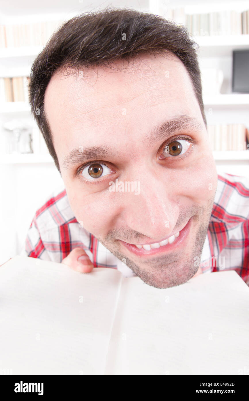 Tema educativo, close up di noce confuso e sconvolto ampia occhi aperti professore o studente con il libro nelle sue mani, atmosfera da salotto con libreria dello sfondo. Pazzo uomo perché eccessiva o di apprendimento styding Foto Stock