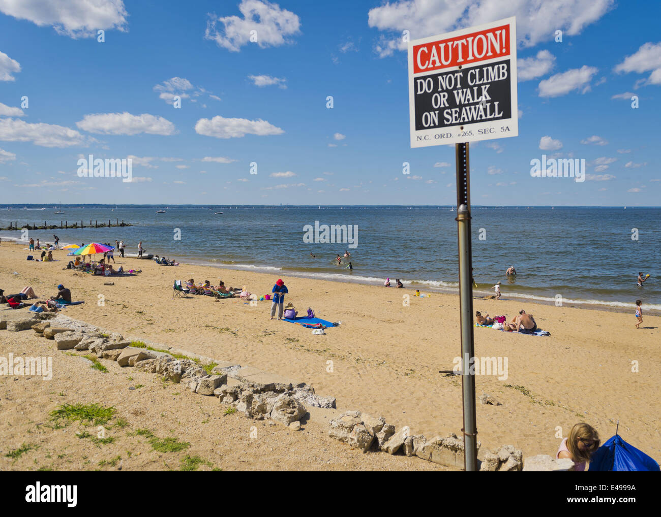 Sands Point, New York, Stati Uniti d'America. 5 Luglio, 2014. Sands Point, New York, Stati Uniti - 5 Luglio 2014 - che si profila un segno di avvertimento attenzione ai visitatori di non salire o camminare sul Seawall sul litorale di Sands Point preservare, sul Long Island Sound Gold Coast. La North Shore spiaggia pubblica ha avuto molti visitatori questo Sabato del lungo giorno di indipendenza week-end di vacanza quando soleggiato clima caldo è arrivato dopo il piovoso luglio 4th. © Ann Parry/ZUMA filo/Alamy Live News Foto Stock