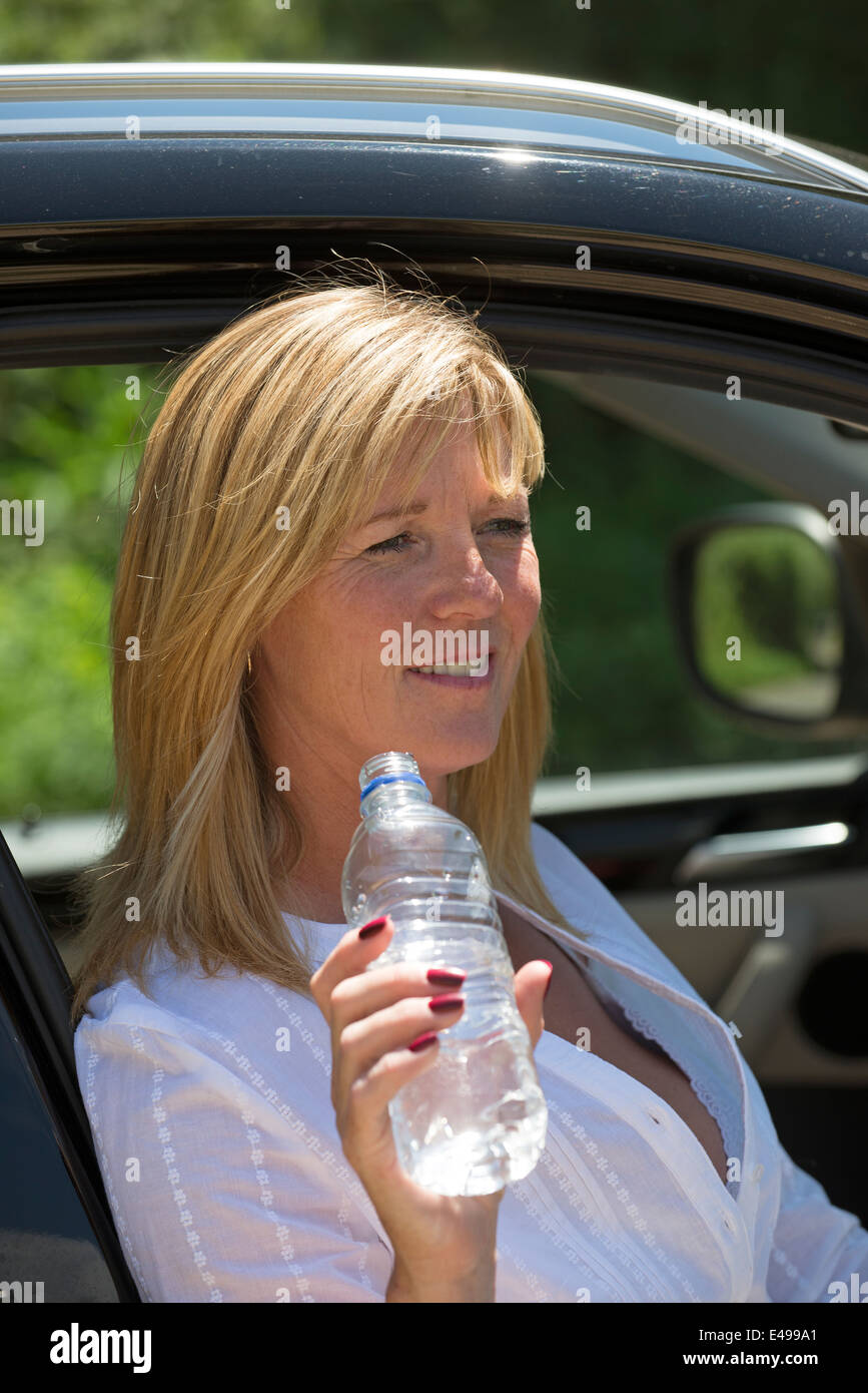 Driver donna acqua potabile da una bottiglia di plastica Foto Stock