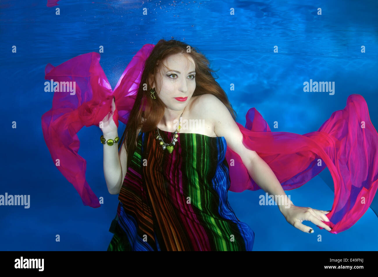 Una giovane donna con grandi capelli in posa di un subacqueo in piscina Foto Stock