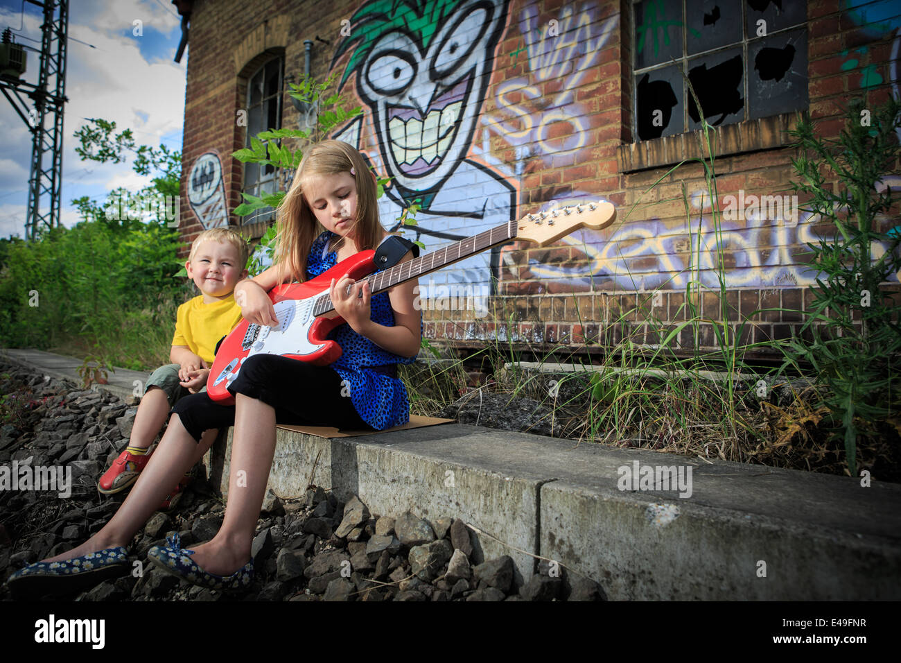 Outdoor ritratto di un piccolo ragazzo e ragazza adolescente con una chitarra Foto Stock