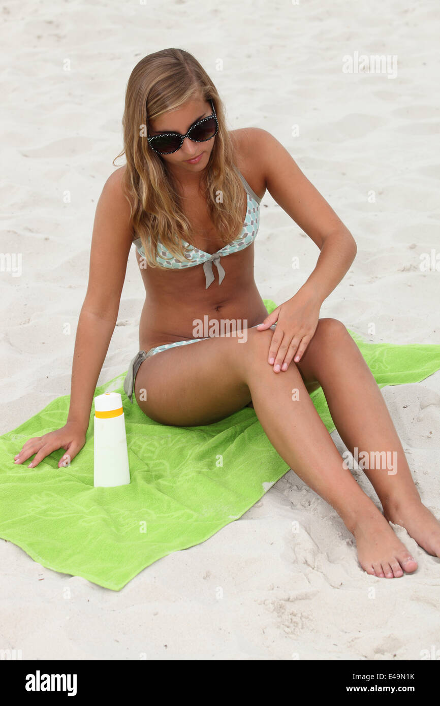 Giovane donna l'applicazione di protezione solare in spiaggia Foto Stock