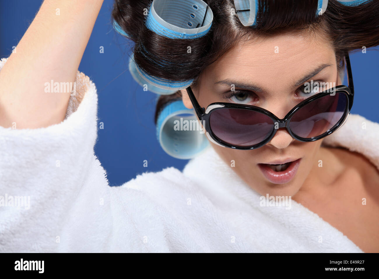 Donna che indossa gli occhiali da sole e i capelli rulli Foto Stock