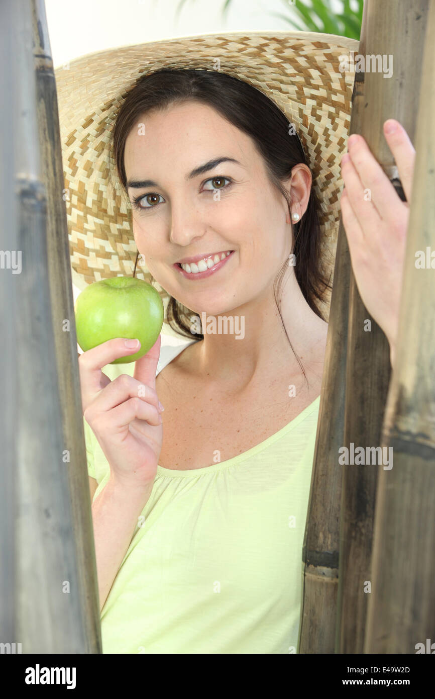 Donna che indossa un cappello e azienda mela verde Foto Stock