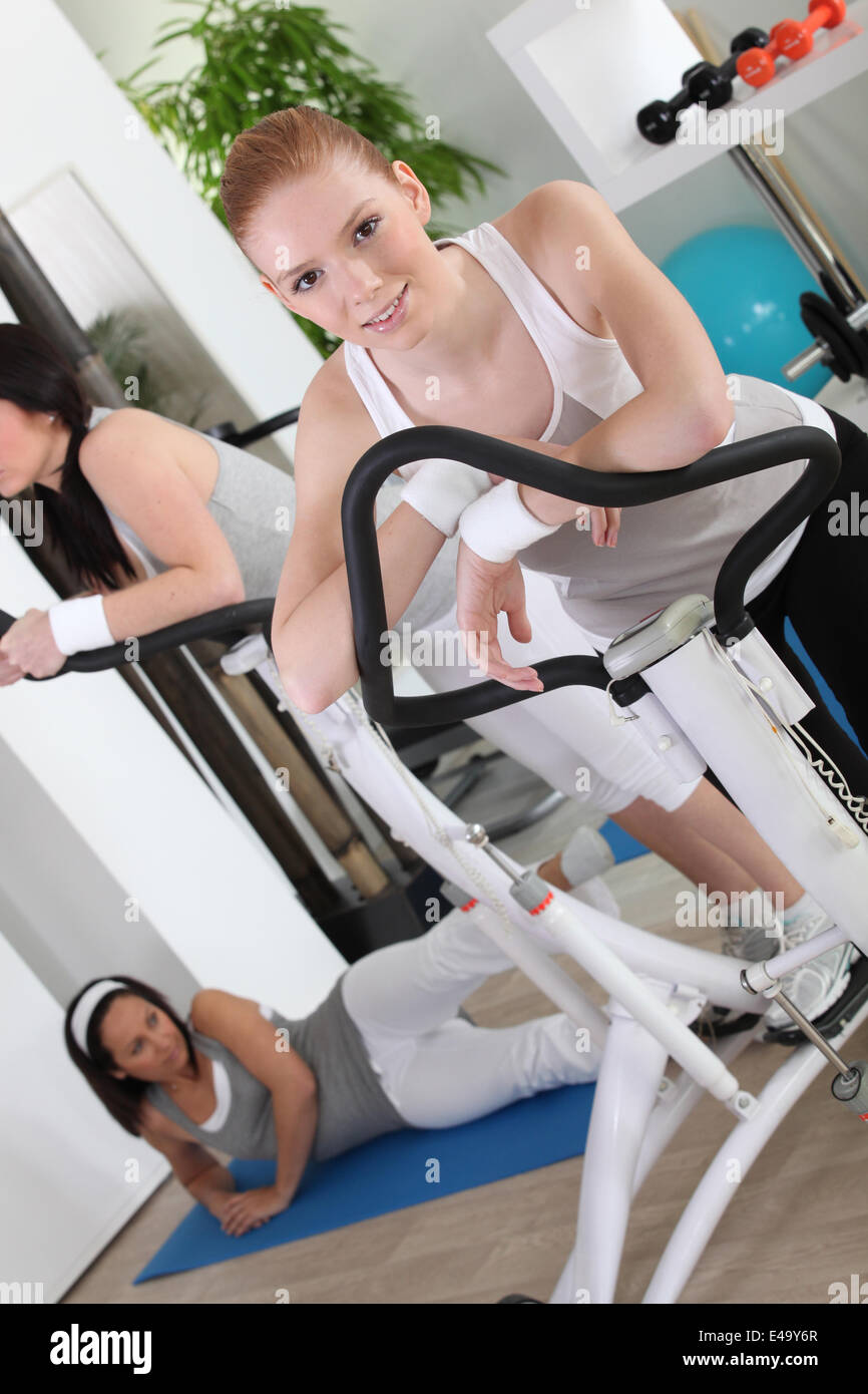 Le donne che utilizzano macchine per esercizi in palestra Foto Stock