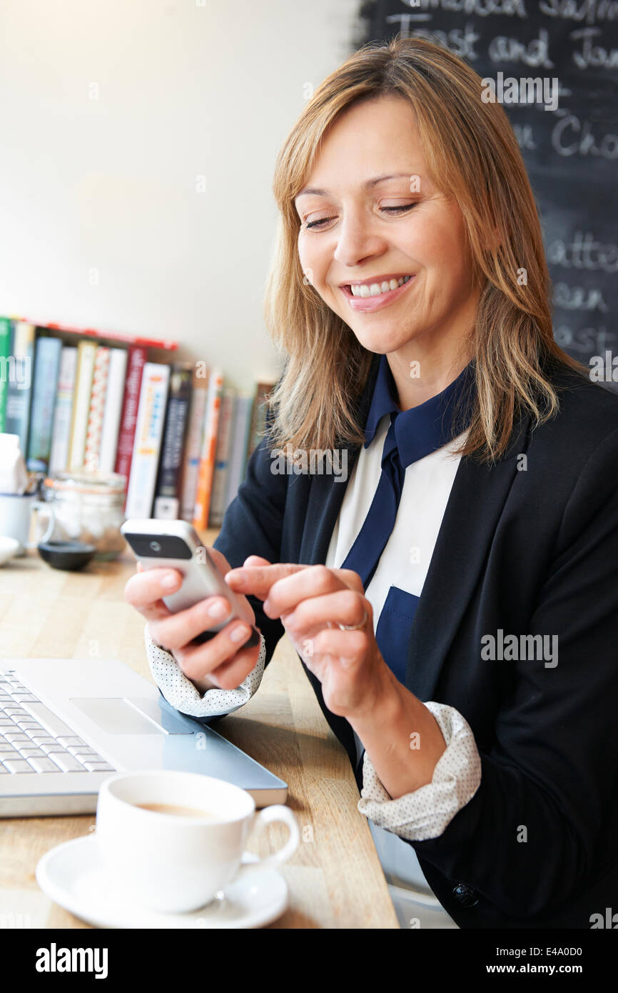 Imprenditrice tramite cellulare in Cafe Foto Stock