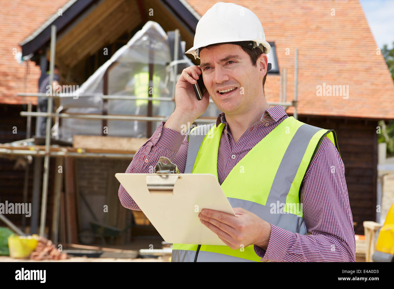 Architetto in cantiere utilizzando il telefono cellulare Foto Stock
