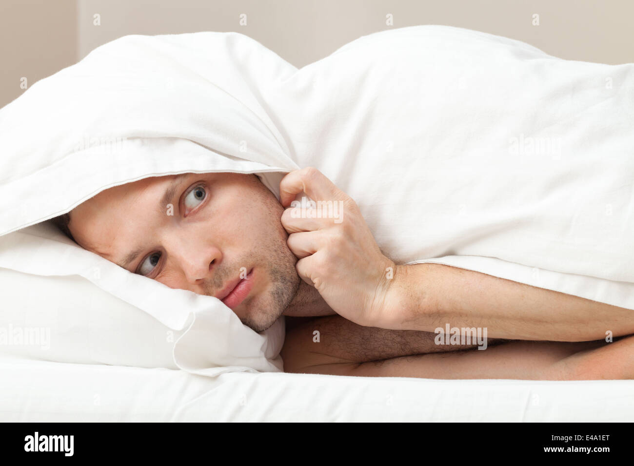 Ritratto di funny spaventata giovane uomo caucasico nel letto Foto Stock