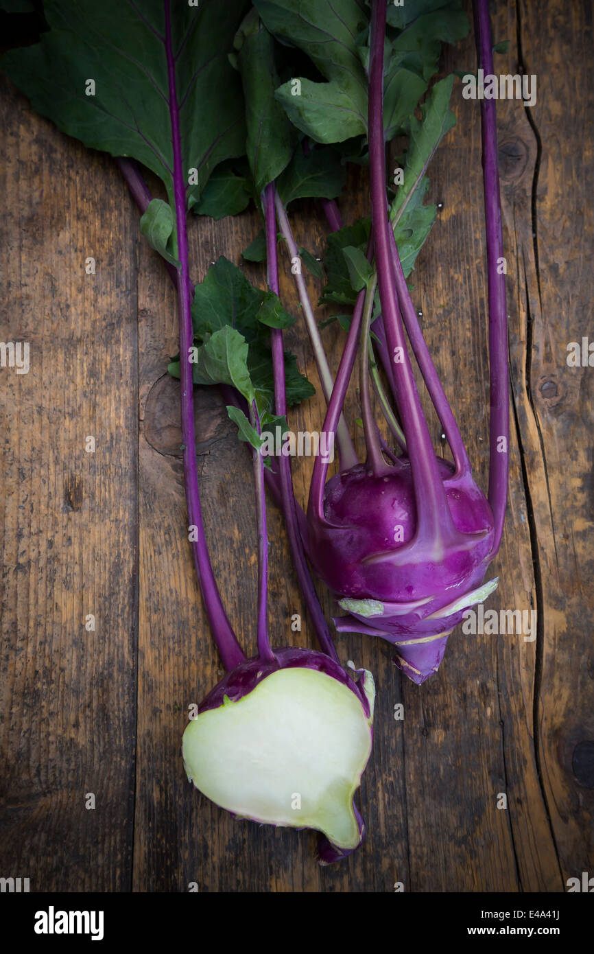 Intero e una metà blu cavoli rapa, Brassica oleracea var. gongylodes L. su legno scuro, vista in elevazione Foto Stock