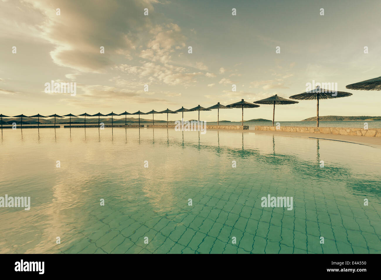 Croazia, Sibenik, ombrelloni, piscina di un hotel facility, atmosfera serale Foto Stock