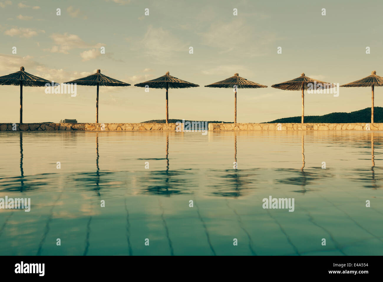 Croazia, Sibenik, ombrelloni, piscina di un hotel facility, atmosfera serale Foto Stock