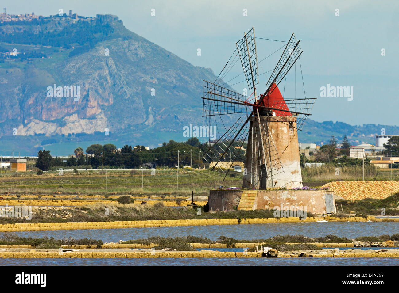 Mulino a vento sulla laguna di Stagnone nella zona delle saline a sud di Trapani, con il Monte Erice in distanza, Marsala, Sicilia, Italia Foto Stock
